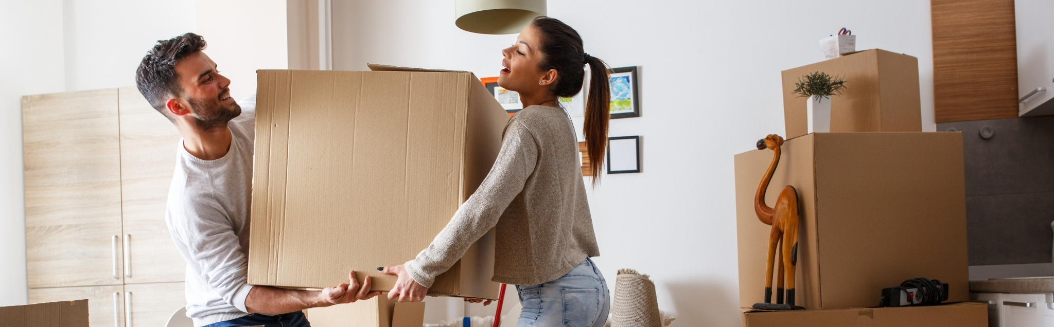 Young couple carrying big cardboard box at new home.Moving house.
