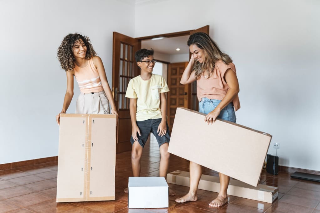A mother and two teenage children with moving boxes